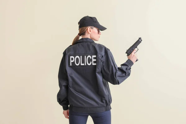 Female police officer with gun on light background
