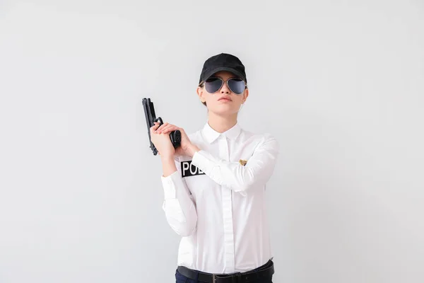 Female police officer with gun on light background