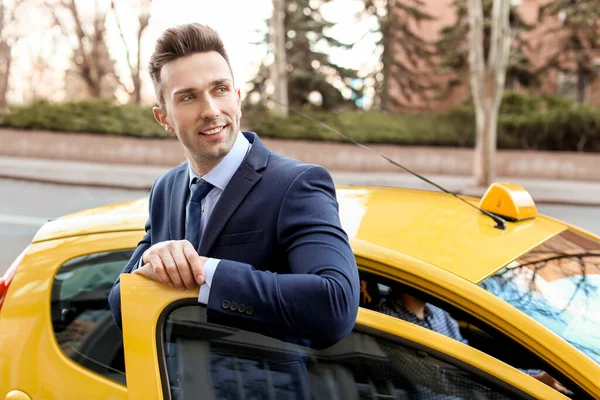 Businessman getting out of taxi on city street