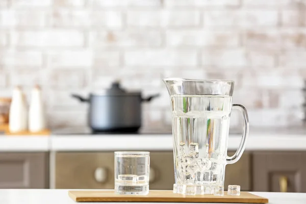 Glass and jug of cold clean water on table in kitchen