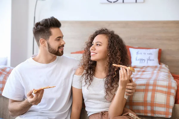 快乐的年轻夫妇在卧室里吃披萨 — 图库照片