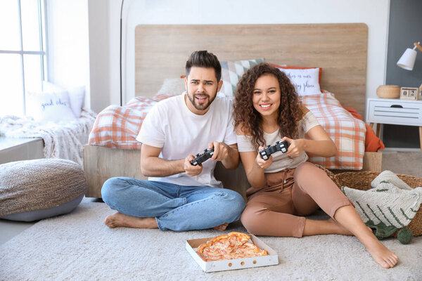 Счастливая молодая пара играет в видеоигры в спальне
