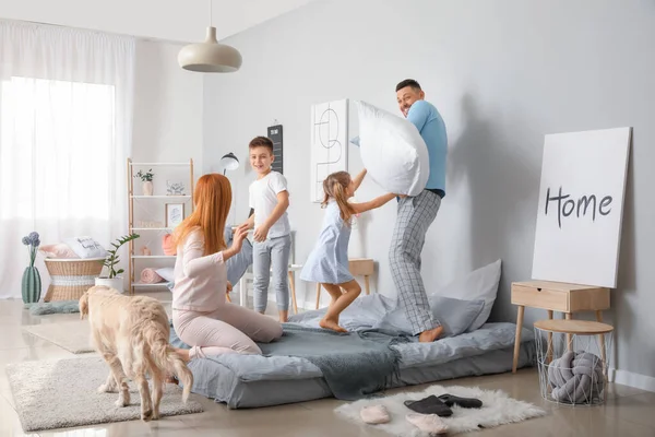 Happy family fighting on pillows in bedroom at home