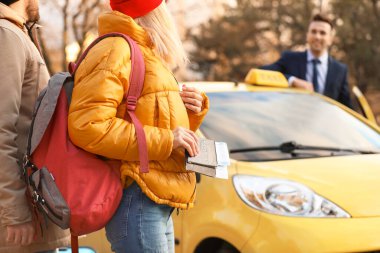 Şehir caddesinde taksiye binen iki turist.