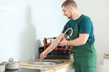 Yakışıklı tesisatçı mutfakta lavabo tamir ediyor.