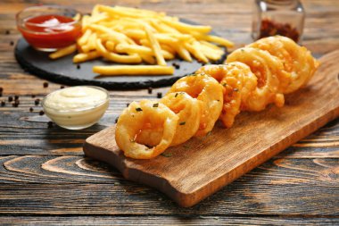 Masada lezzetli soğan halkaları olan bir tahta.