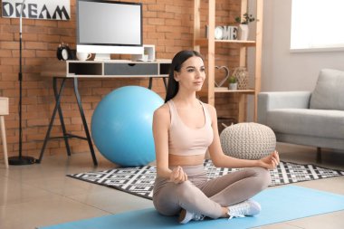 Evde yoga yapan genç bir kadın.