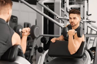 Spor salonunda Dambıl ile sportif genç adam eğitim