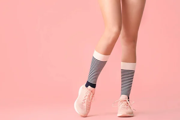 Legs of young woman in socks and shoes on color background