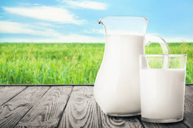 Tarladaki ahşap masada sürahi ve bir bardak süt.