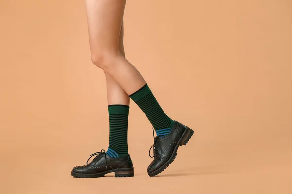 Legs of young woman in socks and shoes on color background