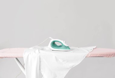 Gri arka planda giysileri olan elektrikli ütü.