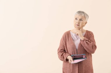 Renk arka planında boş cüzdanı olan yaşlı bir kadın.