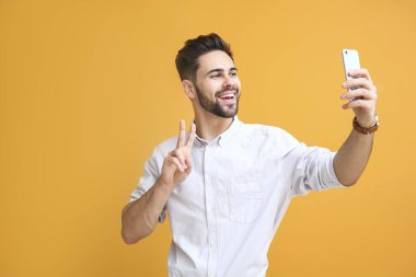 Yakışıklı genç adam renk geçmişinde selfie çekiyor.