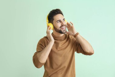 Renkli arka planda müzik dinleyen yakışıklı genç adam.