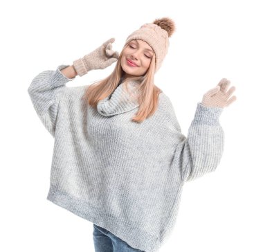 Beyaz arka planda kalın kazaklı, şapkalı ve eldivenli genç bir kadın.