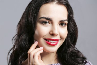 Gri arka planda güzel makyajlı genç bir kadın.