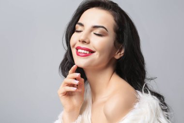 Gri arka planda güzel makyajlı genç bir kadın.