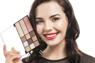 Beyaz arka planda kozmetik ürünleri olan güzel genç bir kadın.