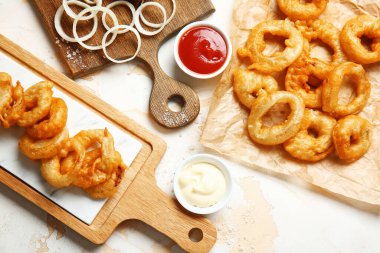 Masanın üzerinde kızarmış soğan halkaları olan kompozisyon.