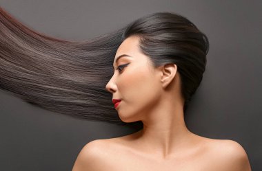 Siyah arka planda güzel saçları olan genç Asyalı kadın.