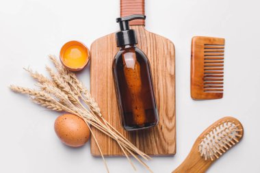 Beyaz arka planda doğal esanslı şampuan, tarak ve fırça