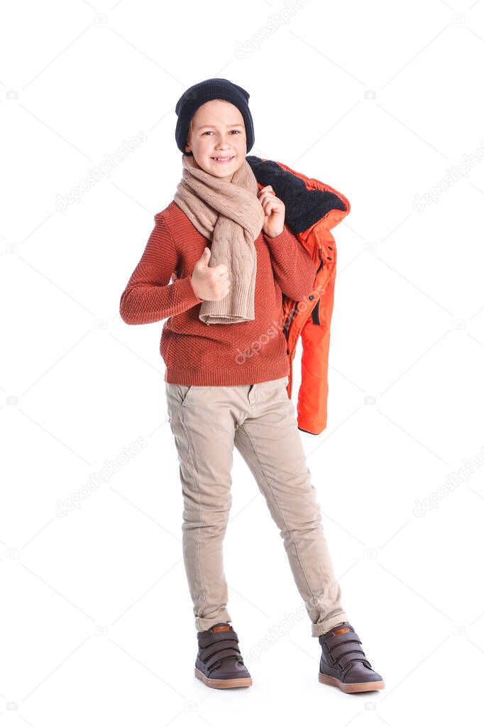 Cute little boy in winter clothes showing thumb-up gesture on white background