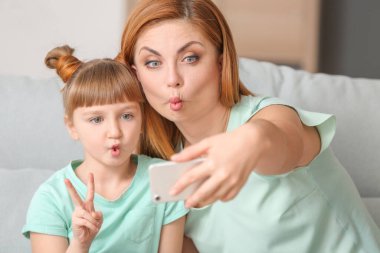 Anne ve küçük kızı evde selfie çekiyorlar.