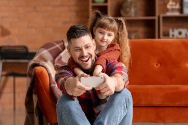 Father and his little daughter taking selfie at home