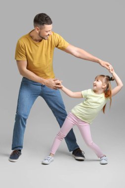 Babası ve küçük kızı gri arka planda dans ediyorlar.
