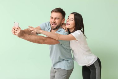 Renkli arka planda erkeğin cep telefonunu almaya çalışan kadın