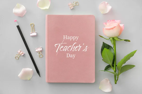 Notebook with text HAPPY TEACHER'S DAY, pencil and rose flower on grey background
