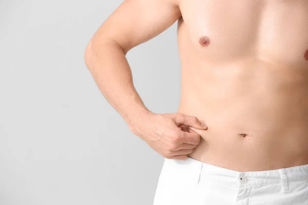 Unge Man Vidrör Magen Fett Ljus Bakgrund Konceptet Plastikkirurgi — Stockfoto