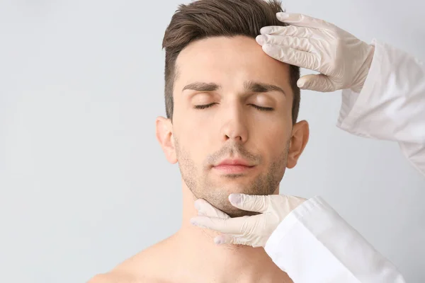 Schönheitschirurg Berührt Gesicht Eines Jungen Mannes Auf Hellem Hintergrund — Stockfoto