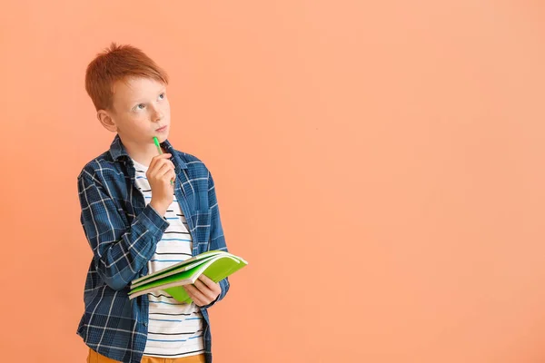 Nachdenklicher Kleiner Junge Mit Stift Und Notizbüchern Auf Farbigem Hintergrund — Stockfoto