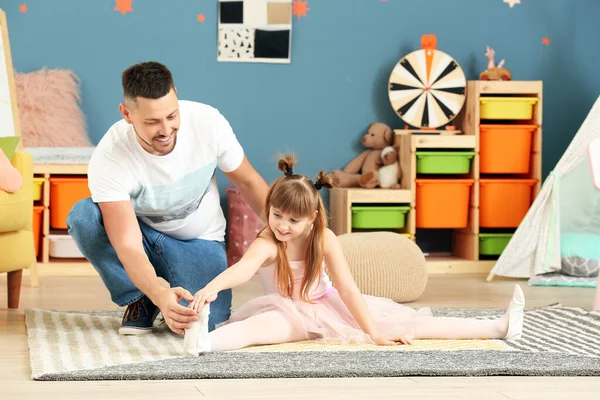 Cute little ballerina and her father having fun at home
