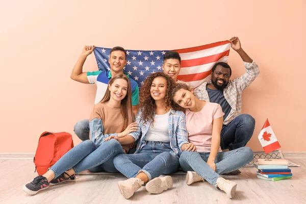 Young students of language school sitting near color wall