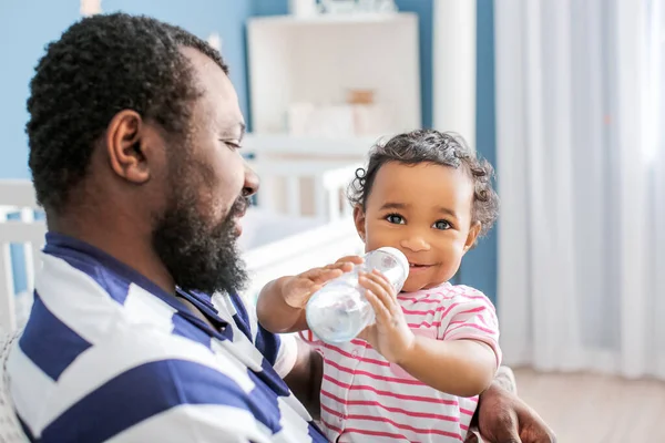 Afro Amerikaanse Man Geeft Water Aan Zijn Schattige Baby Thuis — Stockfoto