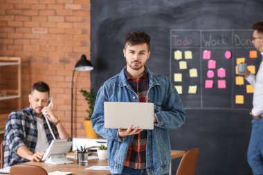 Dizüstü bilgisayarı olan bir adam ve iş arkadaşları ofiste.