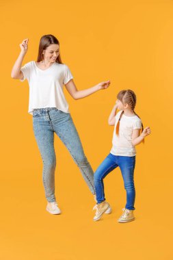 Mutlu anne ve küçük kızı renkli arka planda dans ediyorlar