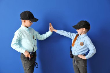 Cute little police officers giving each other high-five on color background clipart