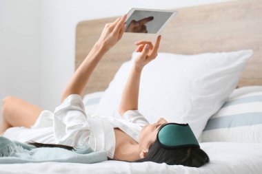 Yatak odasında tablet bilgisayarlı güzel bir genç bayanın sabahı.