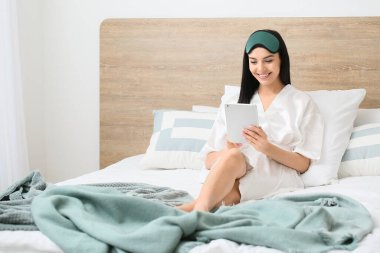 Yatak odasında tablet bilgisayarlı güzel bir genç bayanın sabahı.