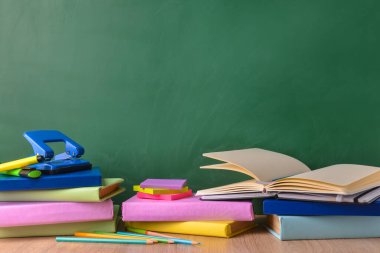 Tahtanın yanındaki masada okul malzemeleri var.