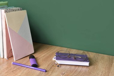 Tahtanın yanındaki masada okul malzemeleri var.