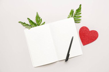 Beyaz arkaplanda kalemi olan boş bir defter