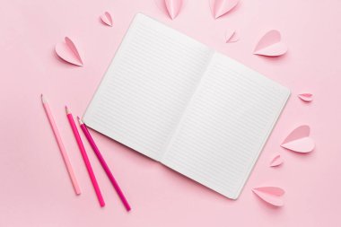 Renkli arka planda kalemleri olan boş bir defter