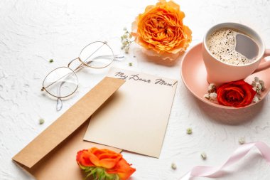 Beyaz zemin üzerinde boş tebrik kartı, zarf ve kahve olan kompozisyon