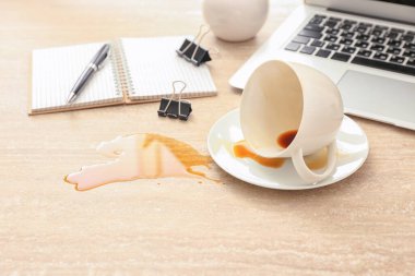 Overturned cup of coffee on office table clipart