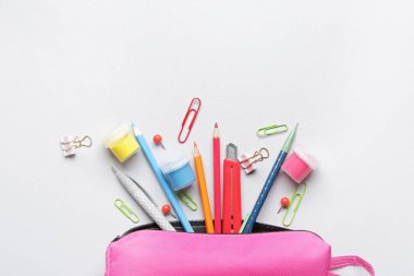 Pencil case and stationery on light background clipart
